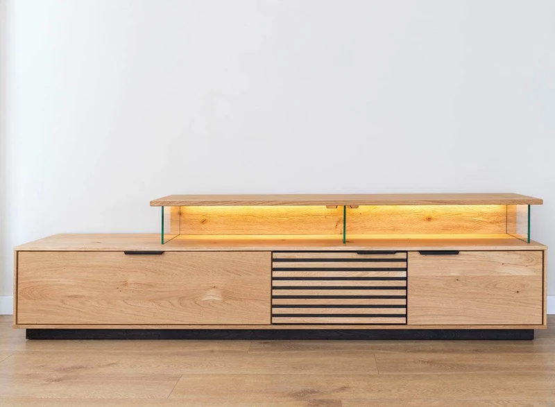 Beleuchtete Hängekommode aus massiver Eiche mit Lamellen | TV-Board Tirano II mit Schaukasten und grober Holzstruktur