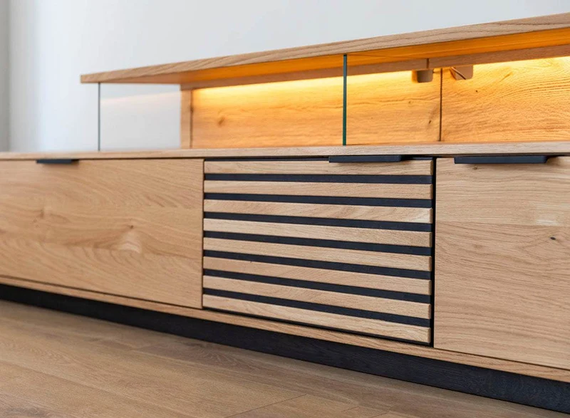 Beleuchtete Hängekommode aus massiver Eiche mit Lamellen | TV-Board Tirano II mit Schaukasten und grober Holzstruktur